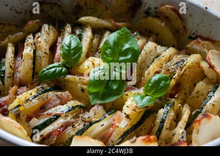 Gebackene Kartoffelgratin Speck und Zucchini, frisch aus dem Ofen auf einem Holztisch serviert.Auflauf Essen, Gefäß. Nahaufnahme. Stockfoto