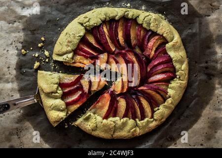 Pfirsich Galette auf Backpapier, ein Stück Gallete auf einer Schaufel, Draufsicht Stockfoto