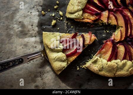 Pfirsich Galette auf Backpapier, ein Stück Gallete auf einer Schaufel, Draufsicht Stockfoto