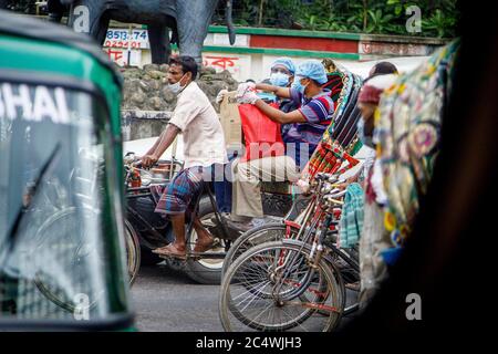 Ricksha-walas, oder Rikscha-Fahrer mit ihren Passagieren auf den Straßen von Dhaka. Die Bewohner der Hauptstadt Dhaka in Bangladesch stellen sich der Bedrohung durch den Corona-Virus COVID 19. Stockfoto