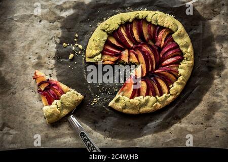 Pfirsich Galette auf Backpapier, ein Stück Gallete auf einer Schaufel, Draufsicht Stockfoto