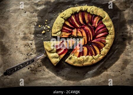 Pfirsich Galette auf Backpapier, ein Stück Gallete auf einer Schaufel, Draufsicht Stockfoto