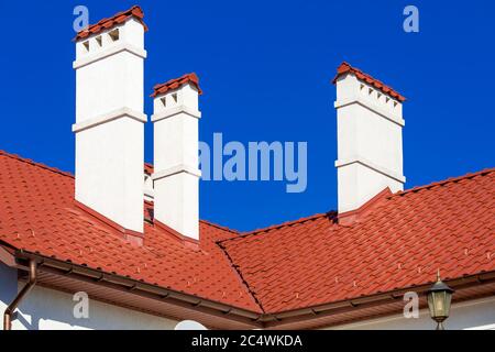 Ein orangefarbenes Dach einer Keramikfliese mit einem Rohr ein Sturmdrainage-System, schließen Details der architektonischen Struktur an sonnigen Tag. Stockfoto