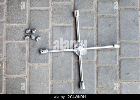 Ein Kreuzschlüssel mit verschiedenen Größen von Köpfen zum Lösen von Radmuttern, ein Werkzeug für den Autoservice liegt auf dem Boden eine Draufsicht. Stockfoto
