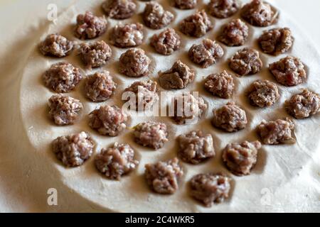 Hackbällchen Füllung für Knödel sind auf dem Teig zum Kochen, Nahaufnahme der Kochen Knödel gelegt. Stockfoto