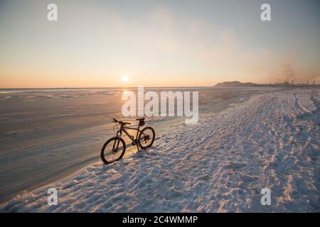 Mountainbike Aufenthalt im Schnee in der Nähe von gefrorenem Meer oder See. Winter Fahrrad Nutzung und Wartung. Nieten Reifen Stockfoto