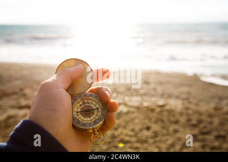 Blickpunkt Foto von Mann hält Kompass in der Hand auf dem Meer und Strand Hintergrund. Stockfoto