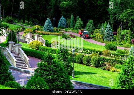 Park für Spaziergänge mit Treppen und Balustern mit einer Vielzahl von grünen Pflanzungen in Form von Bäumen und gut gepflegten getrimmten Büschen an einem sonnigen Tag, in t Stockfoto