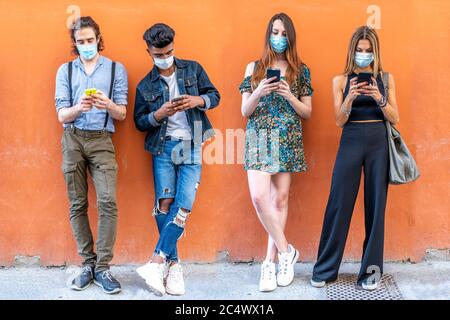 Gruppe von multirassischen Freunden mit Gesichtsmasken, die Smartphones verwenden, um Inhalte in sozialen Netzwerken zu teilen Stockfoto