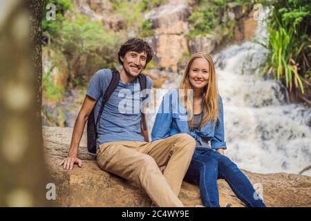 Ein paar Touristen mit Rucksack auf dem Hintergrund eines Wasserfalls Stockfoto