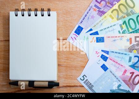 Hintergrund mit Euro-Banknoten mit verschiedenen Werten und Notizblock Stockfoto