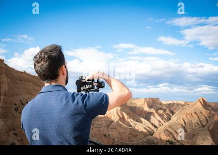 Junge Filmemacherin filmt Naturlandschaft in Canyon mit einem großen Fluss und Sümpfen Stockfoto