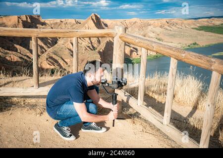 Junge Filmemacherin filmt Naturlandschaft in Canyon mit einem großen Fluss und Sümpfen Stockfoto