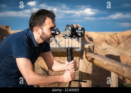 Junge Filmemacherin filmt Naturlandschaft in Canyon mit einem großen Fluss und Sümpfen Stockfoto