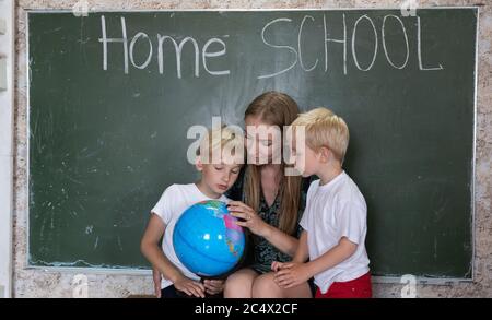 Mutter studiert mit ihren Kindern eine Weltkarte auf einer Erde. Stockfoto