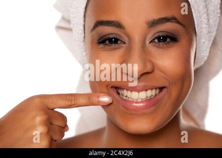 Porträt einer jungen schönen dunkelhäutigen Frau mit einem Handtuch auf dem Kopf, zeigt ihre Zähne Stockfoto