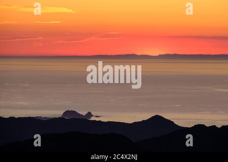 Sonnenuntergang über Ile Rousse und dem Mittelmeer an der Westküste Korsikas mit der Silhouette des französischen Festlandes in der Ferne Stockfoto