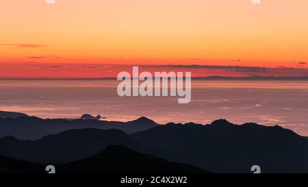 Sonnenuntergang über Ile Rousse und dem Mittelmeer an der Westküste Korsikas mit der Silhouette des französischen Festlandes in der Ferne Stockfoto