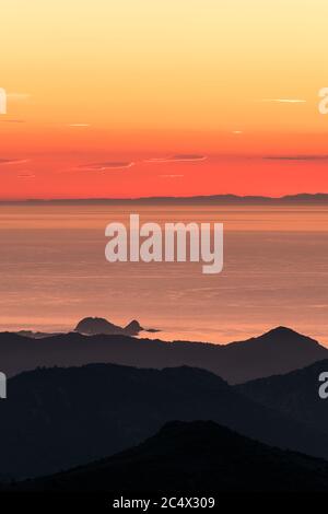 Sonnenuntergang über Ile Rousse und dem Mittelmeer an der Westküste Korsikas mit der Silhouette des französischen Festlandes in der Ferne Stockfoto