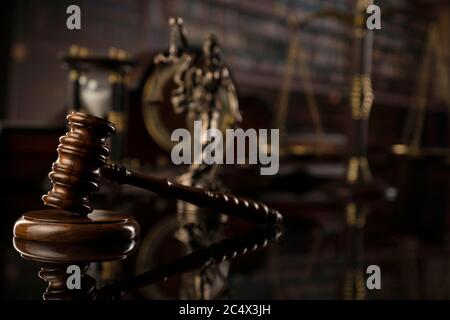 Thema „Recht“. Hofbibliothek. Gavel, Waage und Themis-Statue auf braunem, glänzenden Tisch. Sammlung von juristischen Büchern im Bücherregal. Stockfoto