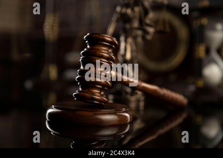 Thema „Recht“. Hofbibliothek. Gavel, Waage und Themis-Statue auf braunem, glänzenden Tisch. Sammlung von juristischen Büchern im Bücherregal. Stockfoto