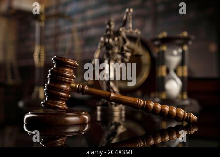 Thema „Recht“. Hofbibliothek. Gavel, Waage und Themis-Statue auf braunem, glänzenden Tisch. Sammlung von juristischen Büchern im Bücherregal. Stockfoto