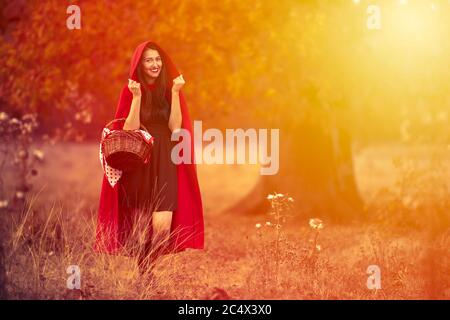 Junge Frau im Rotkäppchen Outfit bei Sonnenuntergang im Wald Stockfoto