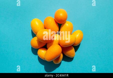 Haufen Kumquats Zitrus isoliert auf blauem Hintergrund. Draufsicht. Viele frische Cumquats Stockfoto