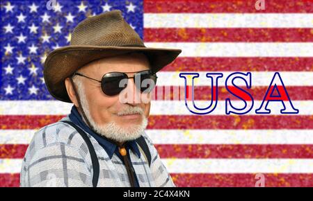 Porträt eines nicht jungen Mannes in einem Cowboy-Hut und Brille mit grauem Bart vor dem Hintergrund der USA-Flagge und der Inschrift USA. Stockfoto