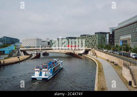 Touristenboote entlang der Spree, Gebäude mit moderner Architektur, Brücke über den Fluss mit vorbeifahrenden Sightseeing-Bussen, Berlin, Deutschland. Stockfoto