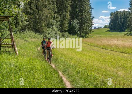 Großmutter mit Elektro-Mountainbike und Enkeltochter ohne elektrische Hilfe auf einem glatten Wiesenweg in der Fränkischen Schweiz bei Bavari Stockfoto