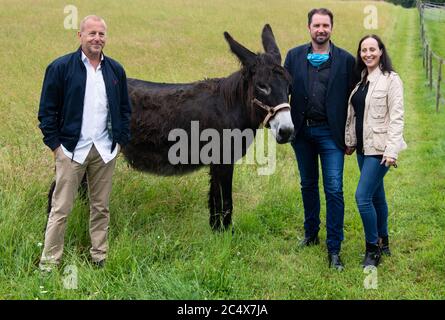 29. Juni 2020, Bayern, Weßling: Heino Ferch (l-r), Schauspieler, Tamer Martin Lacey und Jana Mandana Lacey-Krone nehmen an einer Pressetour auf dem Bauernhof Circus Krone Teil und stehen neben einem Esel. Der Hof beherbergt in der Regel alte Zirkustiere. Aufgrund der aktuellen Situation verbringen einige aktive Tiere in diesem Jahr auch den Sommer auf dem Bauernhof. Foto: Sven Hoppe/dpa Stockfoto