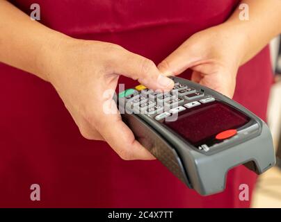 Mann hält eine Zahlung Swipe Maschine und Eingabe, Nahaufnahme. Kreditkartenleser, Kassenterminal-Bezahlkonzept. Stockfoto