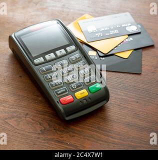 POS-Terminal und Kreditkarten auf Holzhintergrund, Terminal-Kassenautomat für kontaktloses Bezahlen. Bankausstattung, Konsumerismus, Shopping c Stockfoto