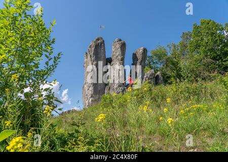 Hübsche ältere Frau unterwegs mit ihrem Elektro-Mountainbike auf einem felsigen Waldweg in der Fränkischen Schweiz, Bayern, Deutschland Stockfoto