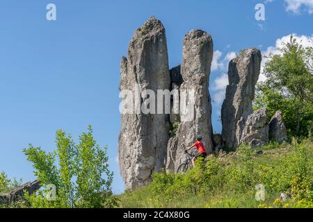 Hübsche ältere Frau unterwegs mit ihrem Elektro-Mountainbike auf einem felsigen Waldweg in der Fränkischen Schweiz, Bayern, Deutschland Stockfoto