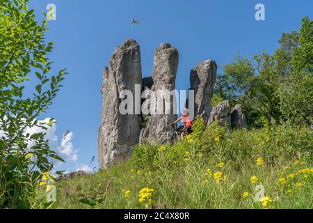 Hübsche ältere Frau unterwegs mit ihrem Elektro-Mountainbike auf einem felsigen Waldweg in der Fränkischen Schweiz, Bayern, Deutschland Stockfoto