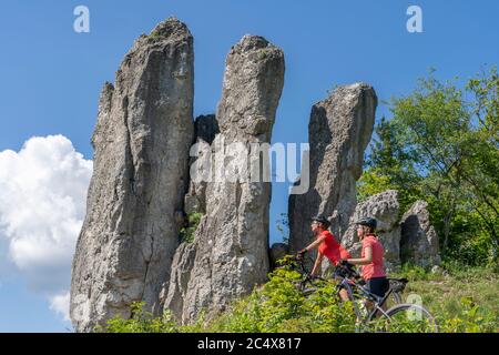 Großmutter und Enkelin fahren mit ihren Mountainbikes in der felsigen Landschaft der Frankonischen Schweiz in Bayern, unterhalb der drei Zinnen Stockfoto