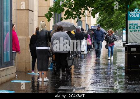 Dundee, Tayside, Schottland, Großbritannien. Juni 2020. UK Wetter: Unbeständiges bewölktes Wetter mit vereinzelten Schauern über Nordostschottland. Der erste Tag der nicht-wesentlichen Geschäfte darf ab heute wieder geöffnet werden, da die Leute draußen im strömenden Regen im Primark Bekleidungsgeschäft entlang des Overbate Einkaufszentrums in Dundee Schlange stehen. Die Mitarbeiter begrüßen die Kunden mit den neuen Covid-19-Richtlinien der Regierung zur sozialen Distanzierung. Kredit: Dundee Photographics/Alamy Live Nachrichten Stockfoto