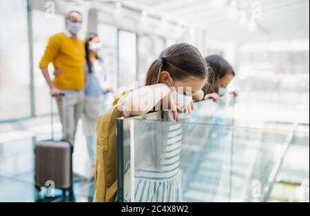 Familie mit zwei Kindern, die in den Urlaub fahren, trägt Gesichtsmasken am Flughafen. Stockfoto