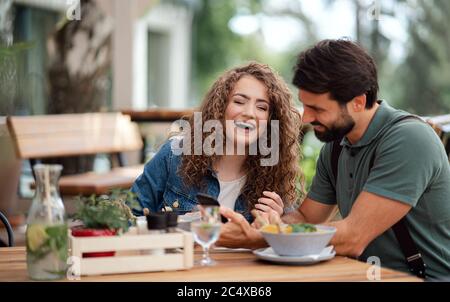 Glückliches Paar sitzt im Freien auf Terrasse Restaurant, mit Smartphone. Stockfoto