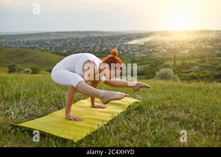 Yoga Meditation in der Natur. Flexibles junges Mädchen, das Yoga auf der Bergspitze bei Sonnenaufgang macht. Stockfoto