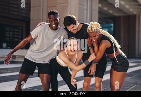 Multiethnische Gruppe von Läufern, die nach dem Training im Freien zusammen stehen und lächeln. Gruppe von Männern und Frauen in Sportbekleidung zusammen stehend Stockfoto