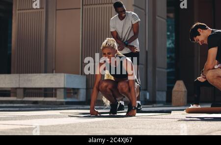 Multi-ethische Männer und Frauen in Sportbekleidung tun Stretching-Training. Gruppe von Menschen, die gemeinsam im Freien in der Stadt trainieren und lächeln. Stockfoto