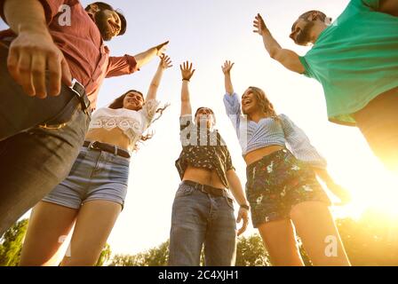 Gruppe junger Freunde, die ihre Hände in Einheit, niedrige Winkel Ansicht. Glückliche Menschen feiern Sieg im Freien Stockfoto