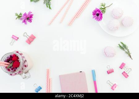 Beeren-Smoothie mit Strohhalmen, Marshmallow, Tagebuch, Stift und rosa Blüten auf weißem Hintergrund. Flach liegend. Stockfoto