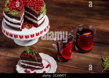 Schöner leckerer Kuchen mit leuchtend roten Beeren auf dem Weihnachtstisch mit duftendem Glühwein mit Gewürzen Stockfoto