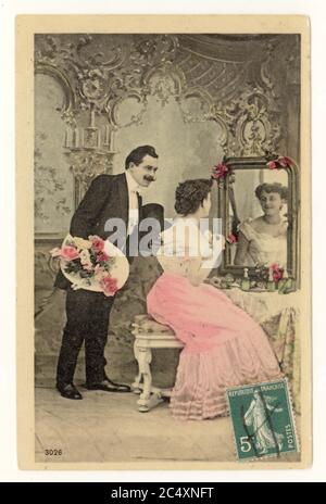 Anfang des 20. Jahrhunderts französische sentimental getönte Grußkarte - zwei junge Liebhaber, Mann mit Blumenstrauß, Frau, die an einem Frisiertisch sitzt, Frankreich, um 1911 Stockfoto