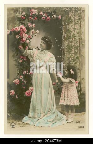 Anfang 1900 ist antike Französisch sentimental getönte Grüße Postkarte - Mutter und nette Tochter hält ihre Hand Kommissionierung Rosen, Frankreich, um 1912 Stockfoto