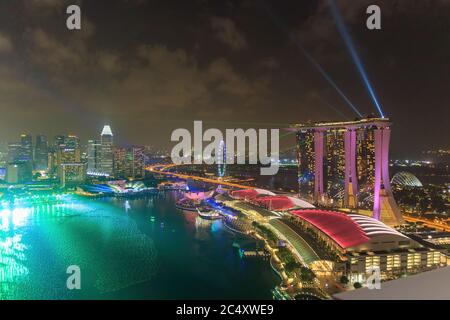 Singapur - UM 2020: Skyline in Marina Bay, Blick auf das Kunstmuseum, das berühmte Hotel und den Singapore Flyer während der Nacht mit einem stürmischen Himmel auf der Rückseite Stockfoto